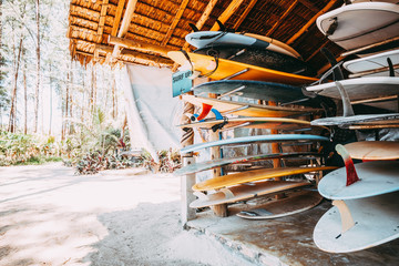 Set of different colorful surf boards in a stack available for rent on the beach. vintage color...