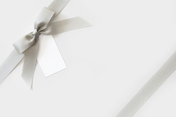 Silver ribbon with a bow as a gift on a white and shiny background