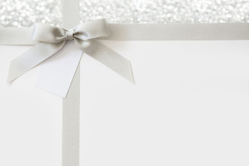 Silver ribbon with a bow as a gift on a white and Shiny background