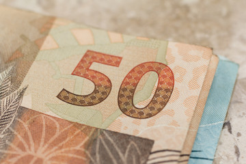 Cash bills from brazilian currency. Closeup on marble table.