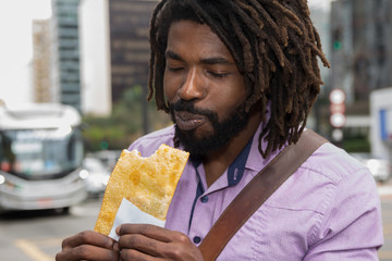 African american man  tasting brazilian snack known as Pastel - asian recipe.