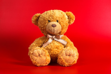 Soft warm cute brown teddy bear on color background. Isolated. Soft red background. Copy space for text.