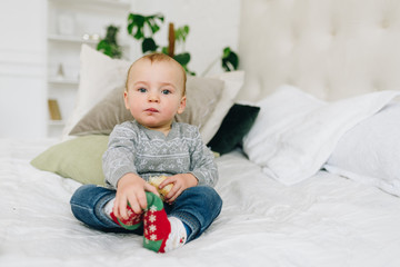 Naklejka premium Cute little toddler boy sitting on bed holding a snack looking straight