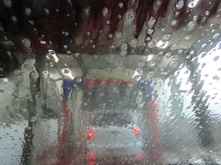 Automatic car wash from inside the car, water with soap bubbles flowing over the windshield window