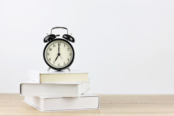 alarm clock with books on wooden desk and white background