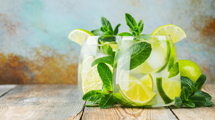 Two Mojito cocktail with ice cubes in a glass on a rustic table, selective focus. With copy space