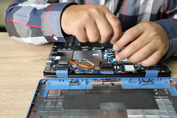 technician man using screwdriver to fix or upgrade laptop computer