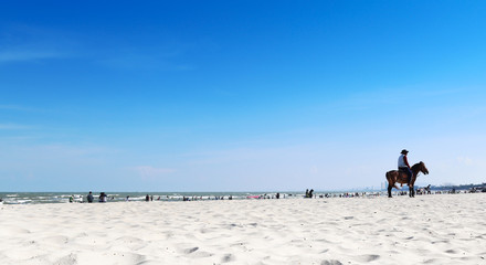White sand and blue sea, There are riders in the right corner.