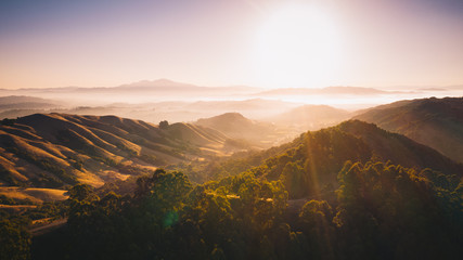 Aerial panoramic background. Sunlight shining on beautiful rolling hills with fog - Powered by Adobe