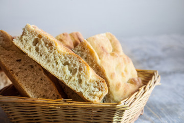 Italian bread of Focaccia Genovese type on display on a basket on a wooden table, sliced in squared...