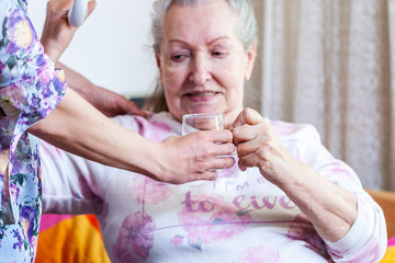 A young woman gives a glass of water to an old woman