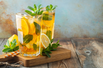 Traditional iced tea with lemon and ice in tall glasses on a wooden rustic table. With copy space