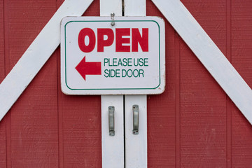 Fototapeta premium Red barn door with the sign : open please use side door