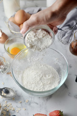 Making pancakes, cake, baking of baker hands pouring flour in bowl. Concept of Cooking ingredients and method on white marble table. Dessert recipes and homemade.