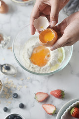 Making pancakes, cake, baking top view of baker hands crack an egg on flour. Concept of Cooking ingredients and method on marble background, Dessert recipes and homemade.