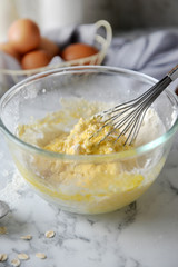 Mixing eggs and flour in bowl. Concept of Cooking ingredients and method on white marble background, Dessert recipes and homemade.