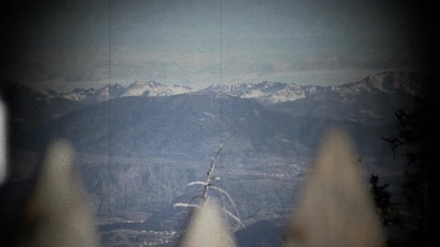 Fake 8mm film projection: a beautiful mountain panorama spotted under a wooden fence.
