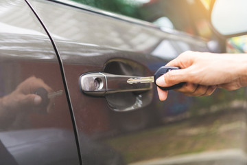 Closeup hand woman holding key opening car door.
