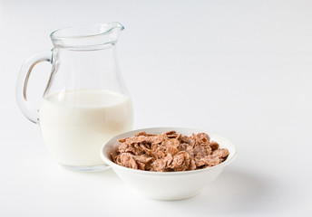 Bowl of multigrain natural flakes and milk jug on a white background. Healthy food. Side view.