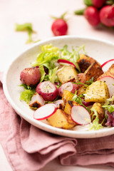 Healthy spring salad with potato, radish and green leaf salad on plate. Roasted vegetables salad....