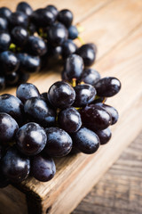 Sweet bunch of black grapes on the rustic background. Selective focus. Shallow depth of field.