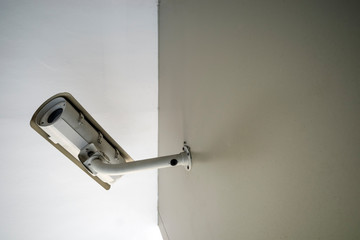 A white CCTV camera on brown wall