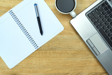 Laptop computer or notebook, note and cup of coffee on working table with copy space top view.