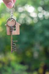 Hanging home key with house keyring with green garden background