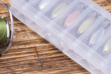 box with different lures on a wooden background next to the spinning reel © kurgu128