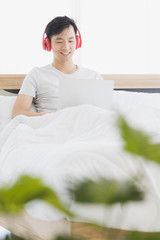 Asian man wearing red headphone, listening music..