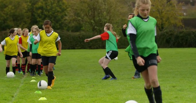 4K Young girls training with the coach at British soccer training academy. Slow motion.