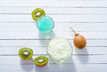 moisturizer and anti aging gel with kiwi on white wooden table