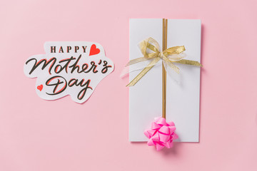 Obraz na płótnie Canvas happy mother's day text, greeting card on pink background, flat lay with space for text. modern image. top view. stylish creative wallpaper.Elegant greeting card with Pink ribbon bow. Creative art.