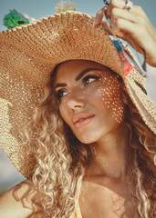 Closeup portrait  Happy curly blonde in a hat on the beach