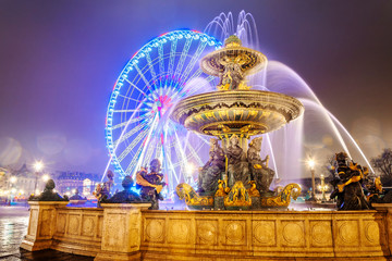 Fountain and illuminated Ferris Wheel at the Place de la Concorde in Paris by night, France