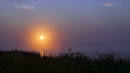 Misty sunrise over the lake in the summer morning