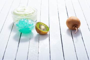 moisturizer and anti aging gel with kiwi on white wooden table