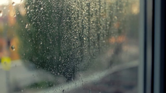 The lights of the night city. Misted glass. Liquid raindrops on the window. Defocused auto traffic lights at sunset day. Sadness and sad mood background.