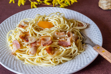 Pasta Carbonara. Flowers in the background. Italian food.
