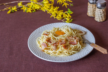 Pasta Carbonara. Flowers in the background. Italian food.
