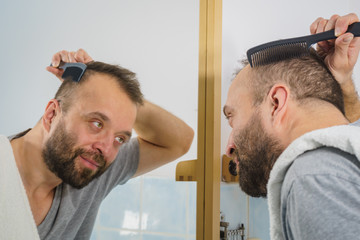 Fototapeta premium Man using comb in bathroom