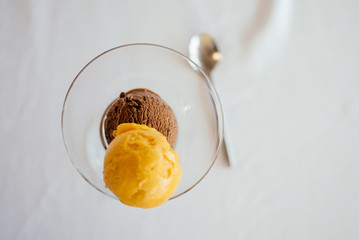 Two scoops of ice cream in a clear glass.