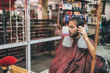 Haircut hair salon man looking in mirror at his hairstyle after barber cut with scissors. Male beauty men care lifestyle.