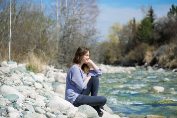 Young girl with positive emotions. Relaxed, pleased with a smile on her face. Spring natural background, forest and river.