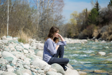 Fototapeta na wymiar Young girl with positive emotions. Relaxed, pleased with a smile on her face. Spring natural background, forest and river.