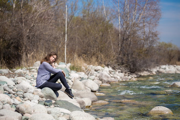 Young girl with positive emotions. Relaxed, pleased with a smile on her face. Spring natural background, forest and river.