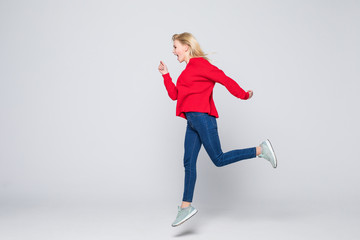 Full length portrait of woman wearing jeans and t-shirt jumping and rejoicing with perfect smile isolated over gray background