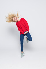 Fototapeta na wymiar Full length portrait of woman wearing jeans and t-shirt jumping and rejoicing with perfect smile isolated over gray background