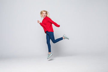 Fototapeta premium Full length portrait of a joyful young woman jumping and celebrating over gray background