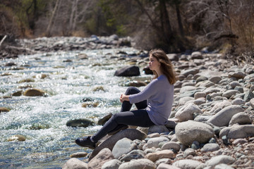 Young girl with positive emotions. Relaxed, pleased with a smile on her face. Spring natural background, forest and river.